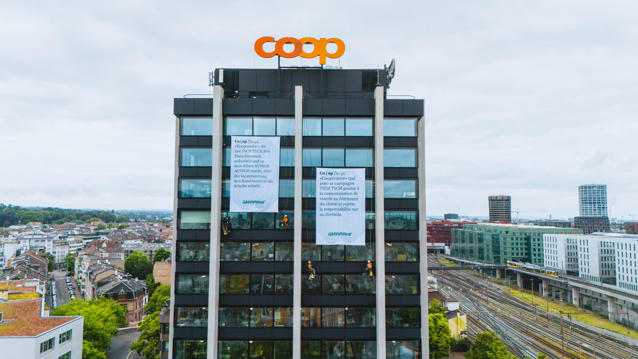 Des militant·es Greenpeace protestent avec de grandes bannières aux sièges de Coop et Migros